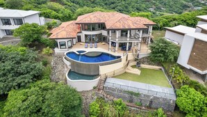 A modern house with a large swimming pool, multiple balconies, and lush greenery surrounding the property. - Luxury House in Mar Vista, Flamingo, Cabo Velas (Playa Flamingo)