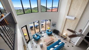 A spacious living area with a high ceiling, large windows offering ocean views, and a ceiling fan. - Luxury House in Mar Vista, Flamingo, Cabo Velas (Playa Flamingo)
