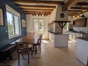 Cozinha espaçosa com mesa de jantar de madeira, armários brancos e bancada embutida.