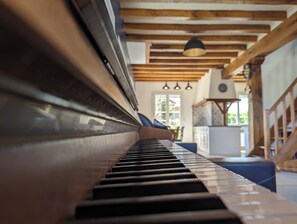 Um piano em um quarto com vigas de madeira e um candelabro.