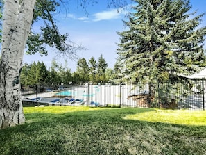 Un espace extérieur clos, doté d’une piscine, et entouré d’arbres et d’herbe.