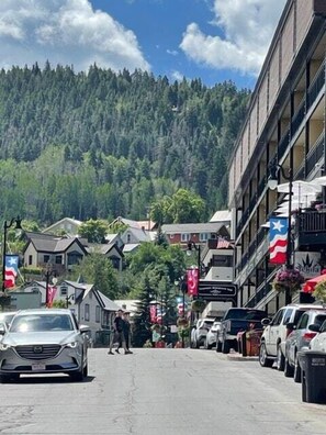 Une rue bordée de voitures garées, d’immeubles et de drapeaux.