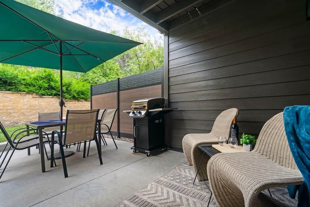 Un patio al aire libre con mesa, sillas, una parrilla y un sofá de mimbre.
