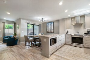 A modern kitchen with a central island, stainless steel appliances, and a dining area with a blue sofa and chairs.