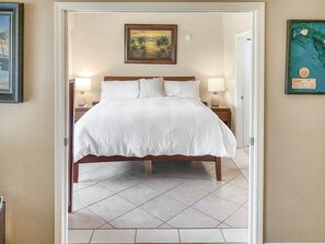 A neatly made bed with white linens, a wooden headboard, and two bedside lamps.