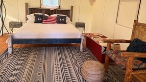 Ein Zeltraum mit einem Bett, einem Sessel und einem kleinen Tisch.