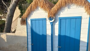 A building with two blue doors and a straw roof. - Villa Stella Marina (Punta Milocca)