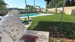 A poolside area with a white umbrella, a decorative white sphere, and a concrete bench. - Villa Stella Marina (Punta Milocca)