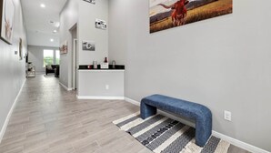 Ein Flur mit einer Bank, einer Küchenzeile mit Arbeitsfläche und einem großen Gemälde an der Wand.