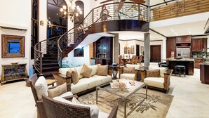 A spacious living area with a curved staircase, a dining area, and a kitchen with dark wooden cabinets. - Playa Hermosa Luxe Villa • 4BR • 5BA • Infinity Pool & Ocean Views (Playa Hermosa)