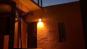 A building with a staircase leading to a balcony, a wall-mounted light, and a palm tree. - Old World Caribbean with new world amenities (Belle Vue)