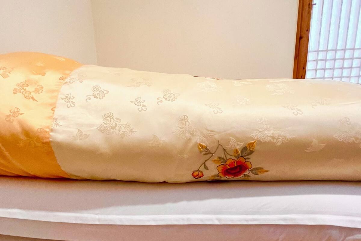 Ein Bett mit einer floralen Decke und einem schlichten weißen Matratze.