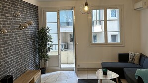 A modern living room with a brick wall, a sofa, a coffee table, and a potted plant. - Très bel Appartement Neuf T4 (Toulon)