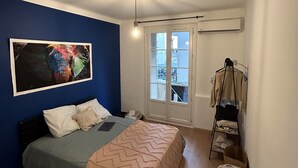 A bedroom with a bed, a blue wall, a window, and a hanging light fixture. - Très bel Appartement Neuf T4 (Toulon)