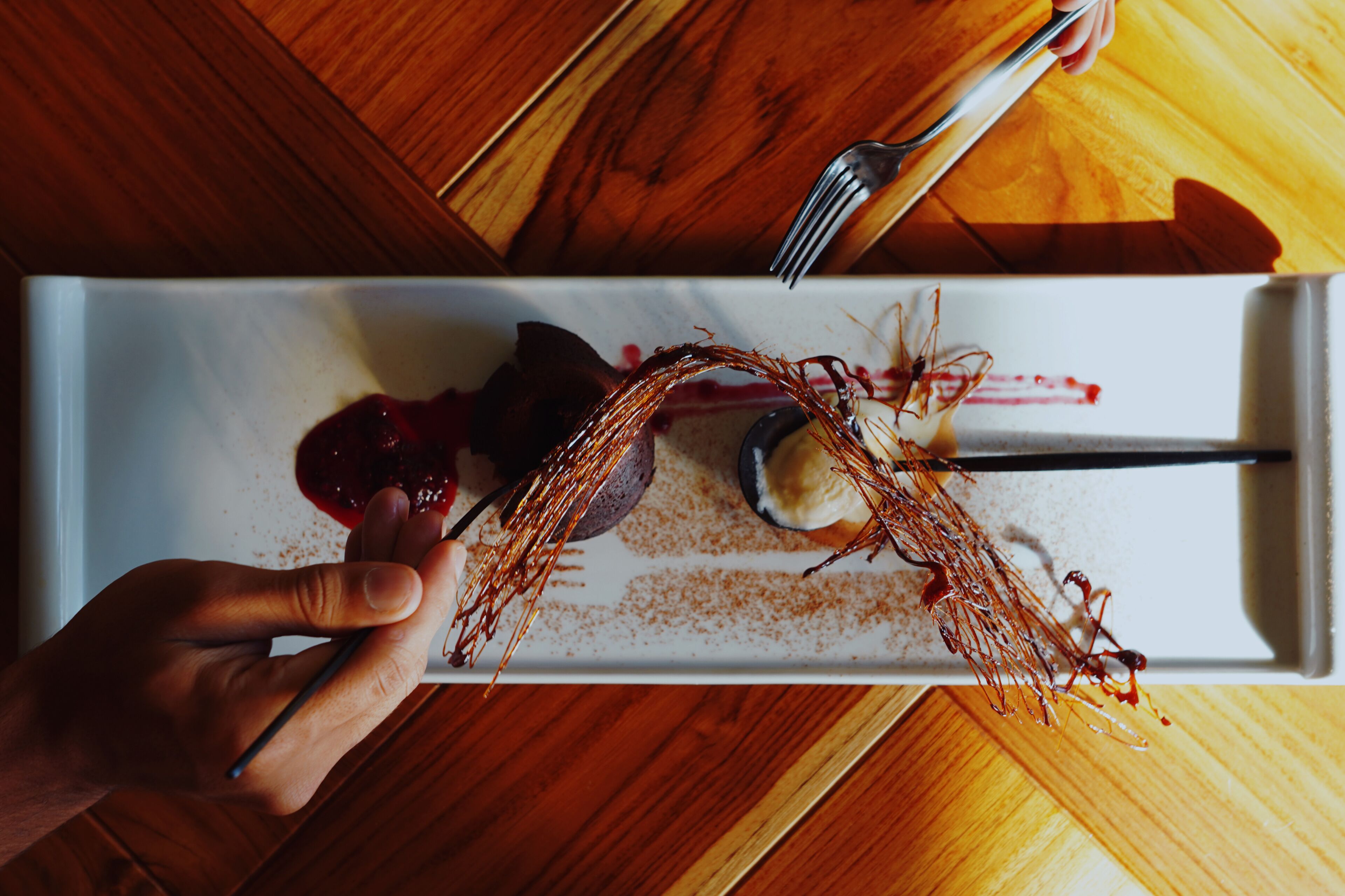 A dessert plate with a fork and spoon on a wooden table.