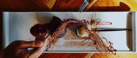 A dessert plate with a fork and spoon on a wooden table.