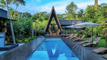 Alberca al aire libre, sombrillas en la alberca y camastros