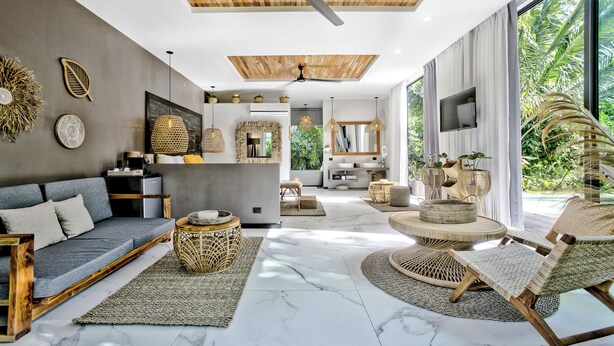 A modern living room with a sofa, wicker furniture, a ceiling fan, and a large window with a view of greenery. - Namu Garden Hotel & Spa - Adults Only (Cahuita)