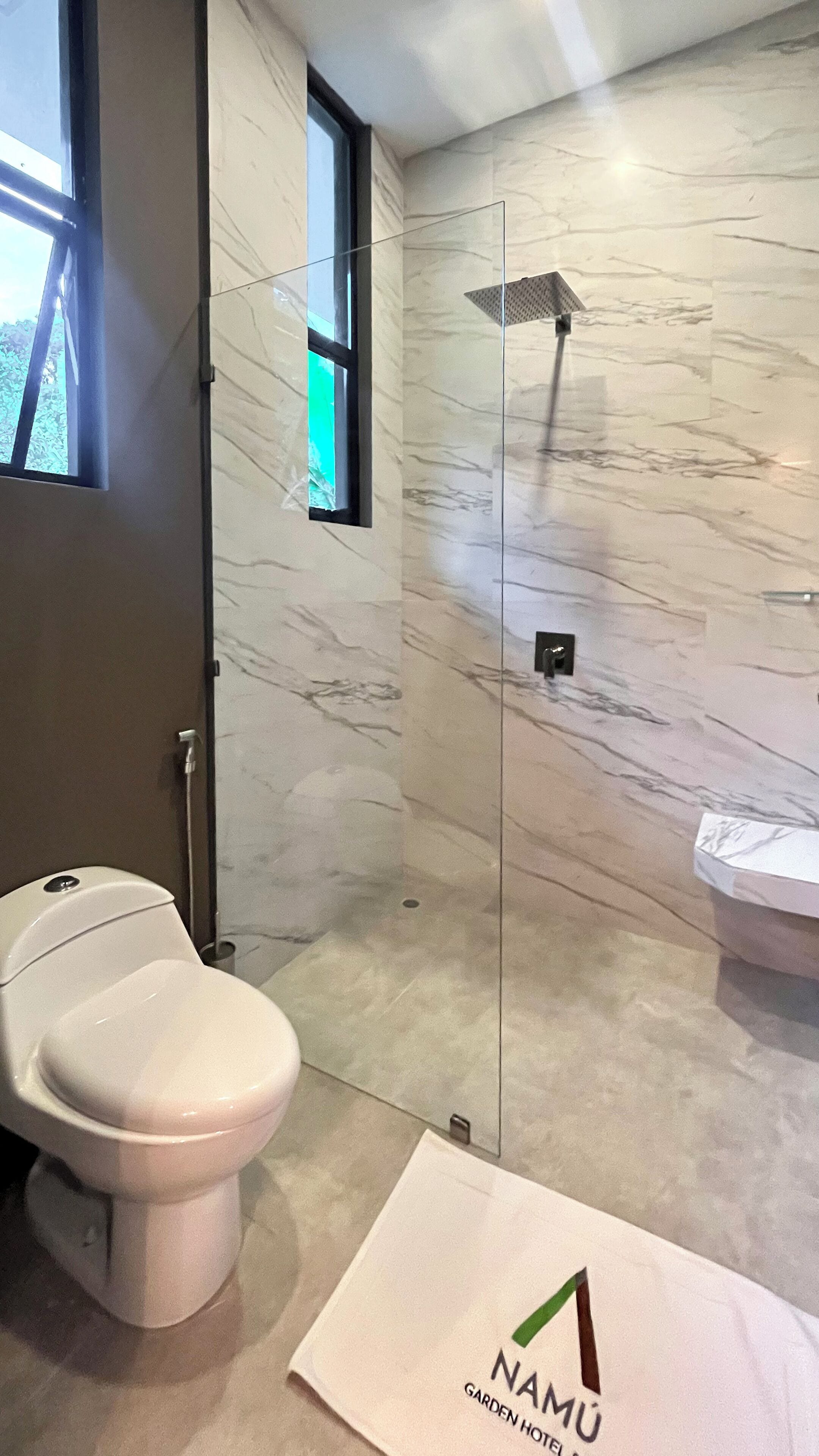 Un baño moderno con inodoro, cabina de ducha de vidrio y lavabo.
