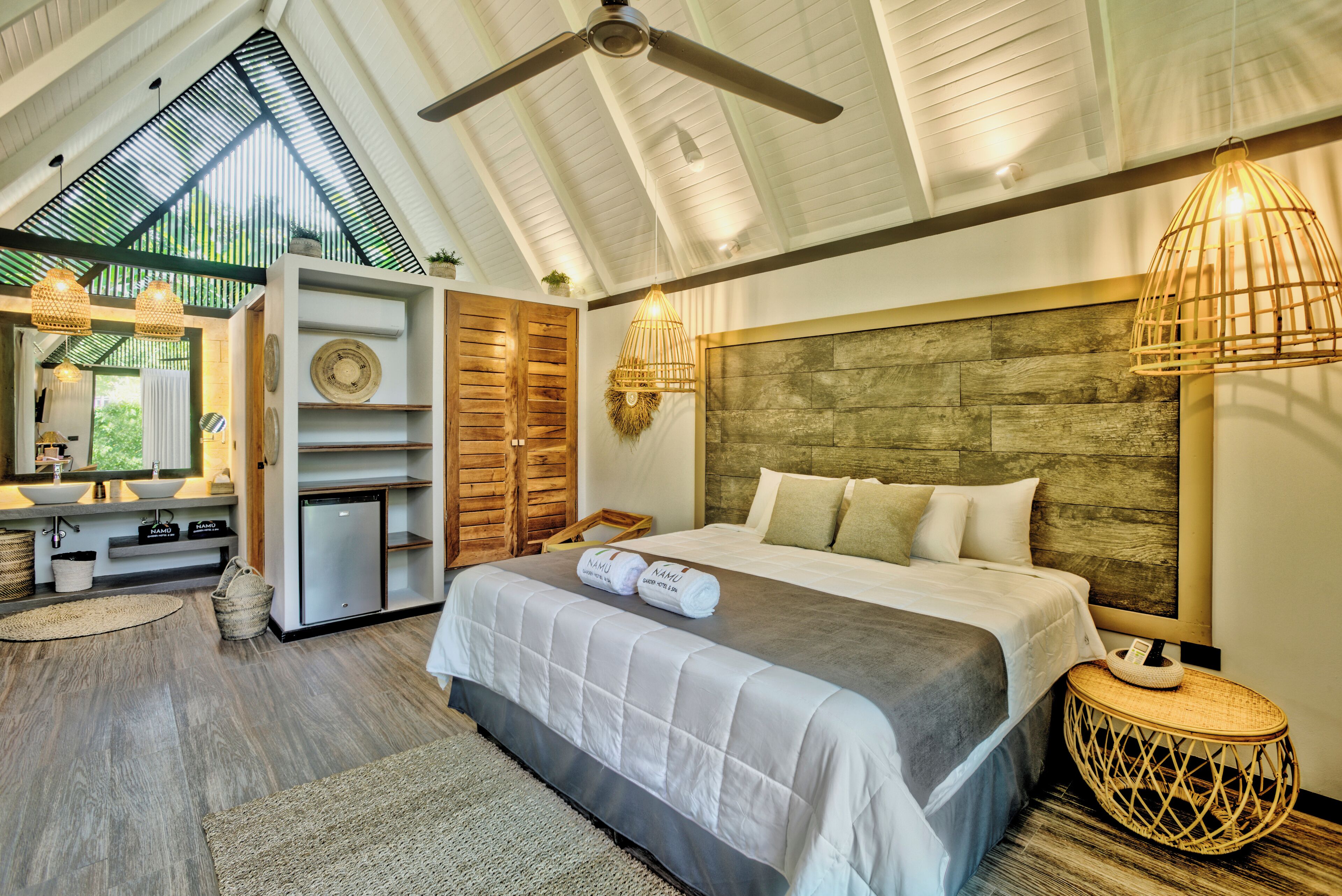 A bedroom with a large bed, wooden headboard, and a ceiling fan.