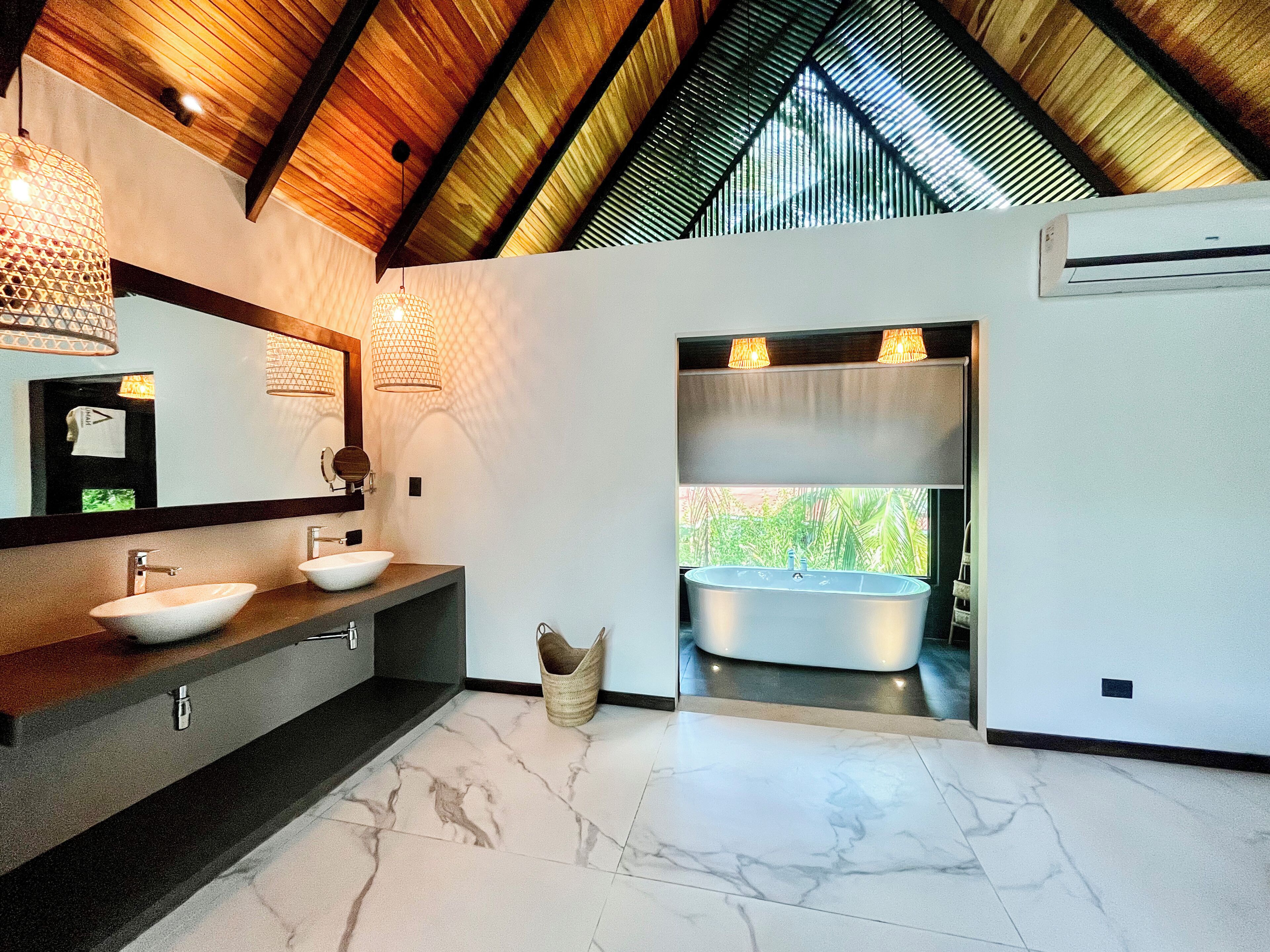 Ein modernes Badezimmer mit einem großen Spiegel, zwei Waschbecken, einer Badewanne und einem Deckenventilator.