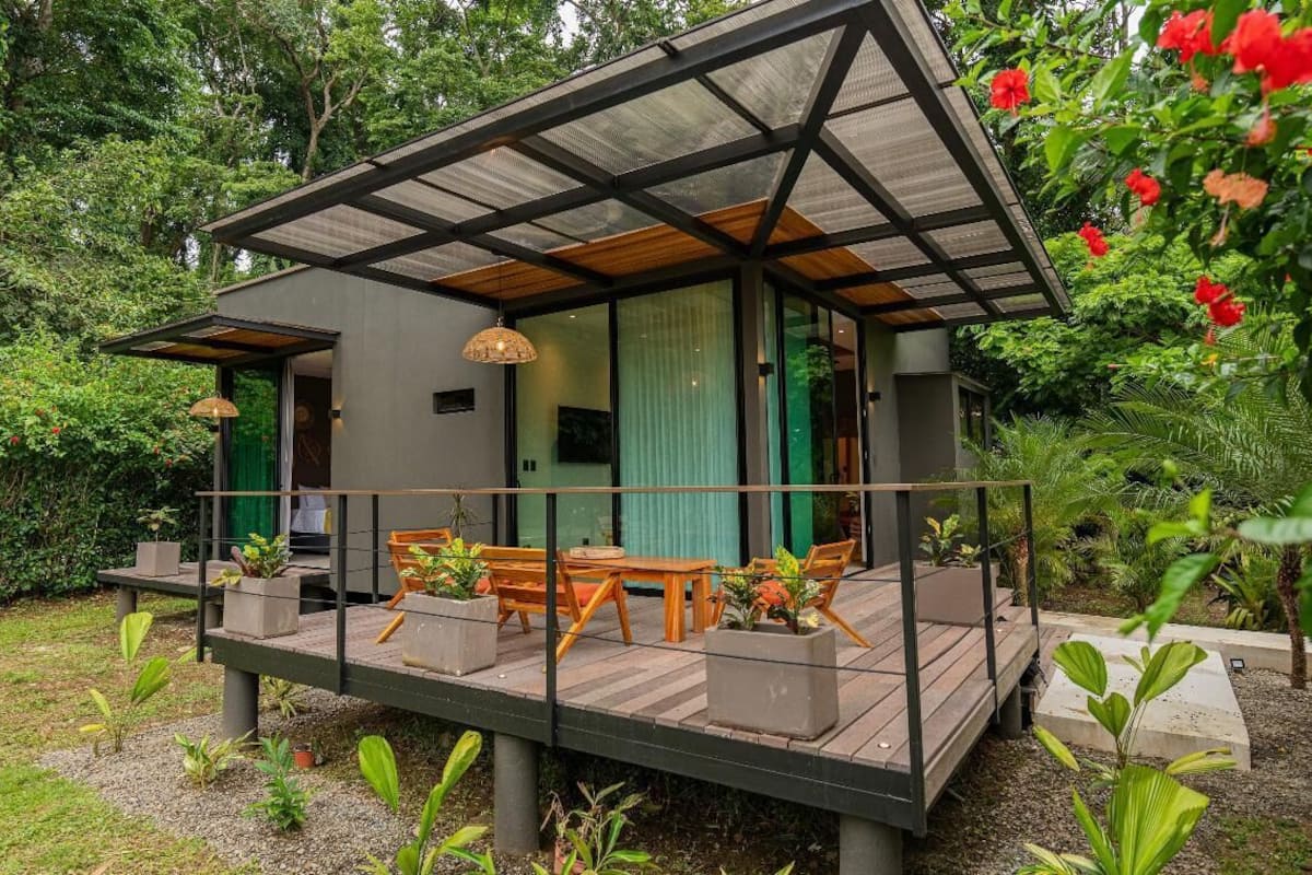 Une maison moderne dotée d’une terrasse couverte, de grandes fenêtres et d’un jardin.