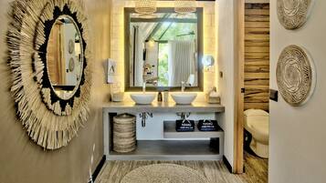 A modern bathroom with a large mirror, two sinks, and a ceiling skylight.