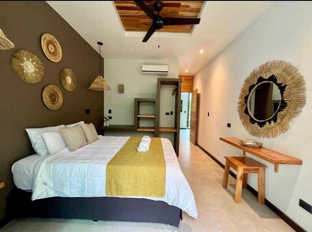 A bedroom with a bed, a wooden bench, a mirror, and wall decor.
