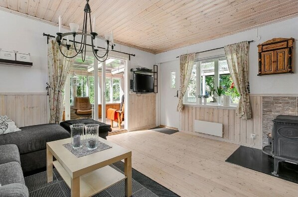 A cozy living room with a fireplace, a TV mounted on the wall, and a dining area with a table and chairs.