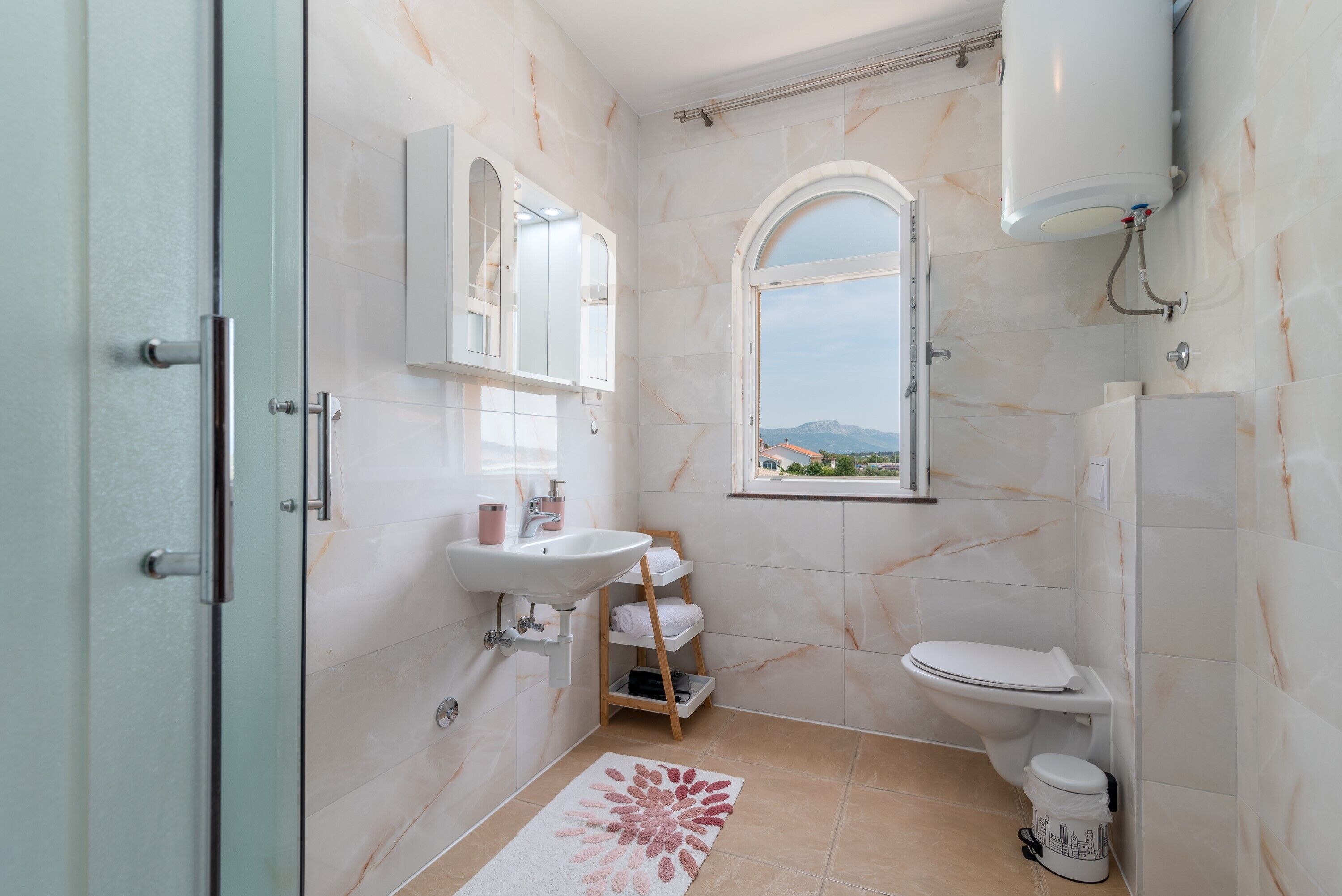 Un baño con ducha, inodoro, lavabo y una ventana con vistas.