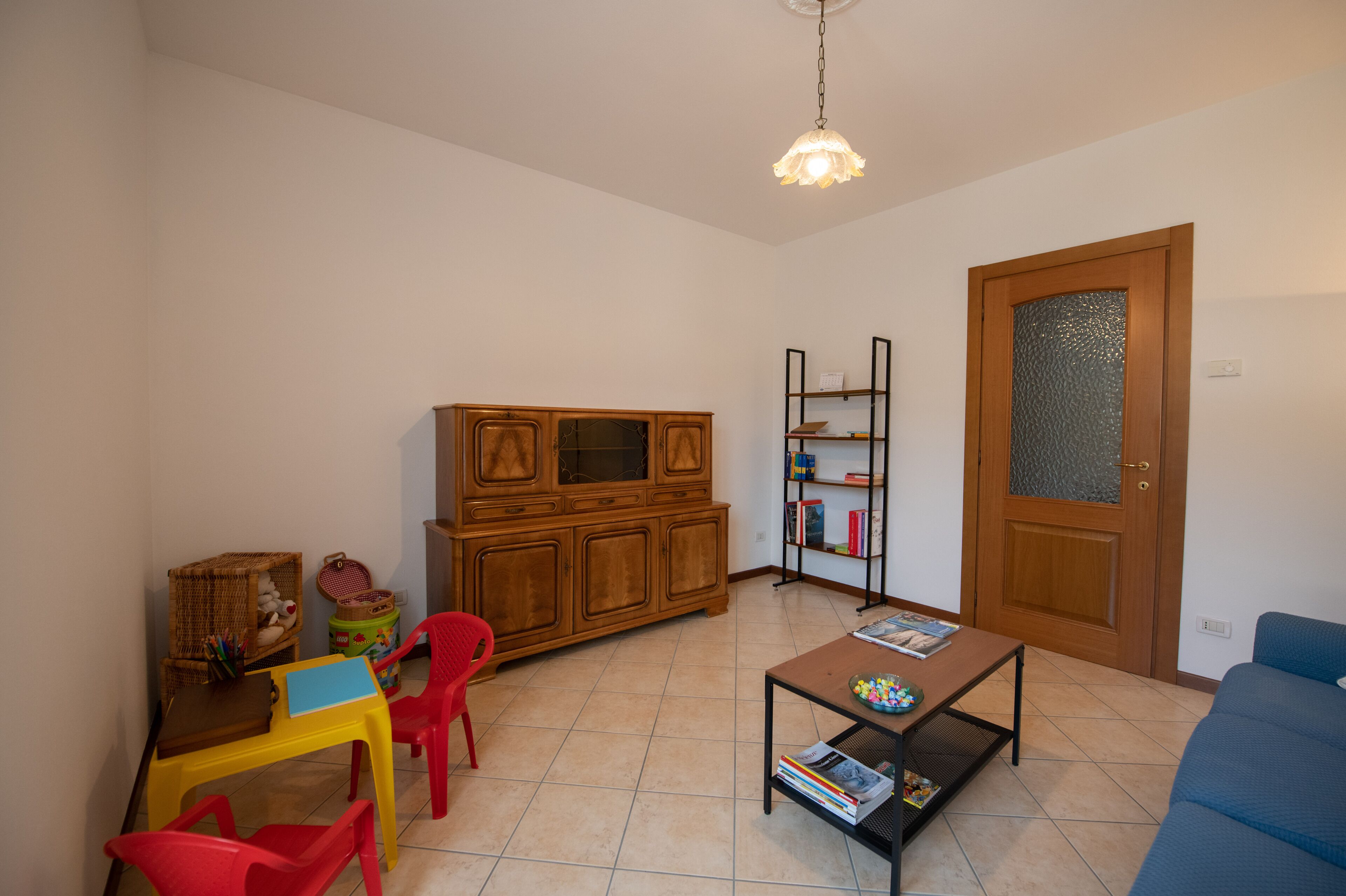 A compact living space with a wooden cabinet, a bookshelf, a dining table with chairs, and a sofa.