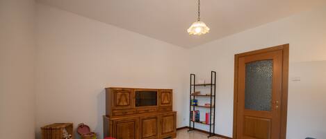 A compact living space with a wooden cabinet, a bookshelf, a dining table with chairs, and a sofa.