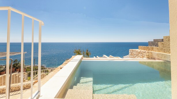 A clear blue sky, a swimming pool, and a view of the sea.
