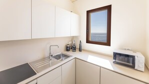 A compact kitchen with a sink, stove, and microwave.