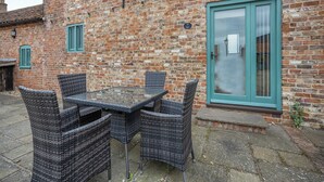 A brick building with a glass door and a table with wicker chairs.