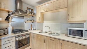 A modern kitchen with stainless steel appliances, wooden cabinets, and a built-in oven.