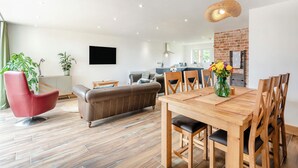 Un salon moderne comprenant un coin repas, un fauteuil rouge, un canapé marron et une table en bois.