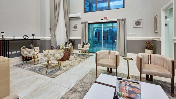 A spacious lobby with a high ceiling, a large window, and a modern reception area. - The Mayflower Inn (Kwabenya)
