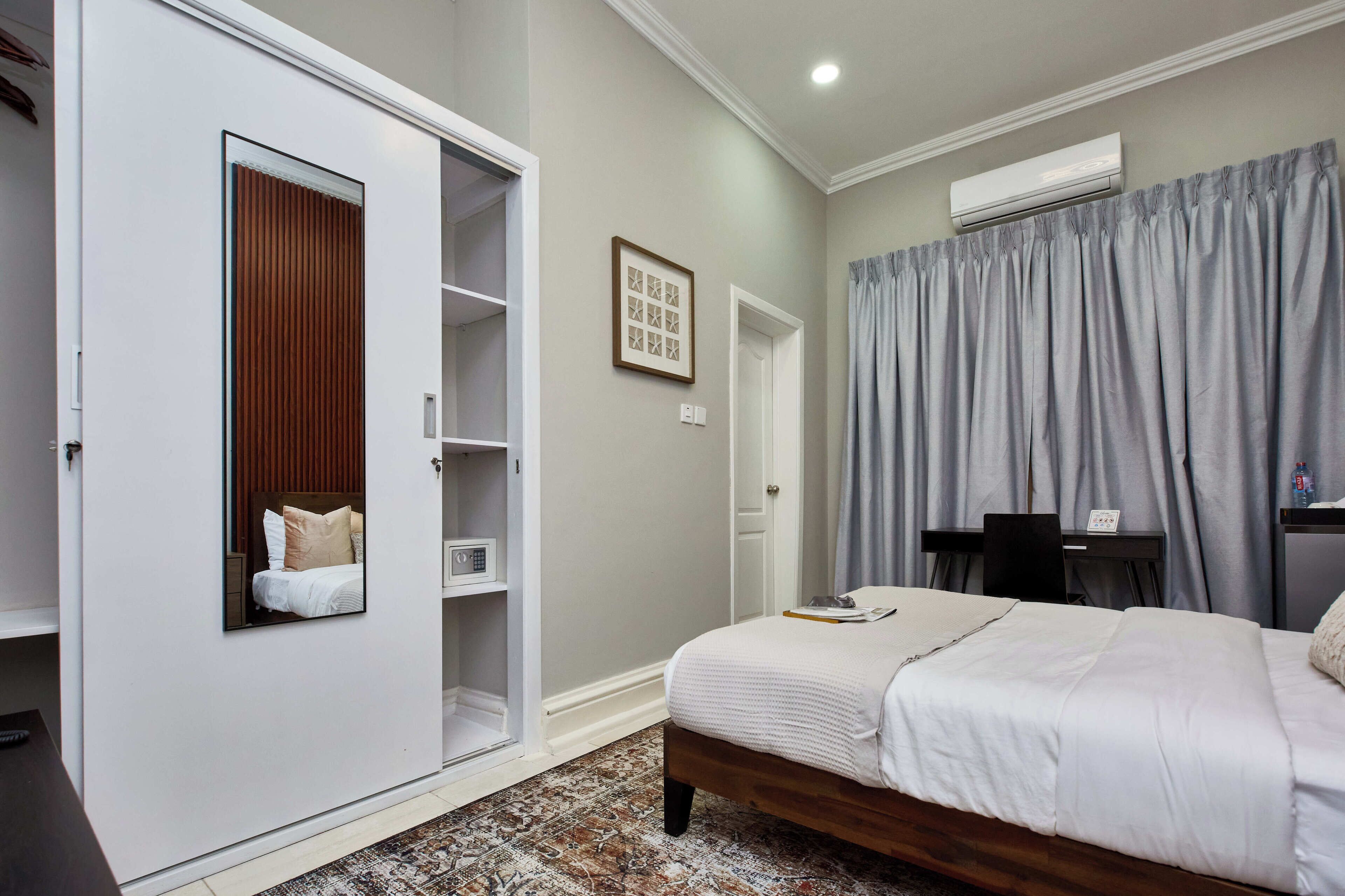 Une chambre à coucher comprenant un lit, une armoire, un bureau et un appareil de climatisation.