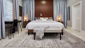 A bedroom with a large bed, bedside tables, a desk, and a chair. - The Mayflower Inn (Kwabenya)