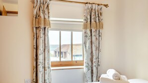Ein Schlafzimmer mit Bett, Fenster und Vorhängen.
