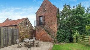 A brick tower with a wooden staircase, a stone building with a red-tiled roof, and a wooden fence. - The Granary - UK44490 (Sedgefield)