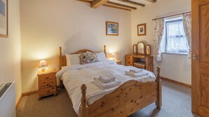 A bedroom with a wooden bed, bedside tables with lamps, a dresser, and a window with curtains. - The Granary - UK44490 (Sedgefield)