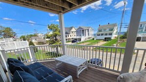 A wooden deck with a white railing, a white table, and a blue cushioned sofa. - Great home minutes from beautiful Moody Beach, for the perfect beach vacation! (Wells)