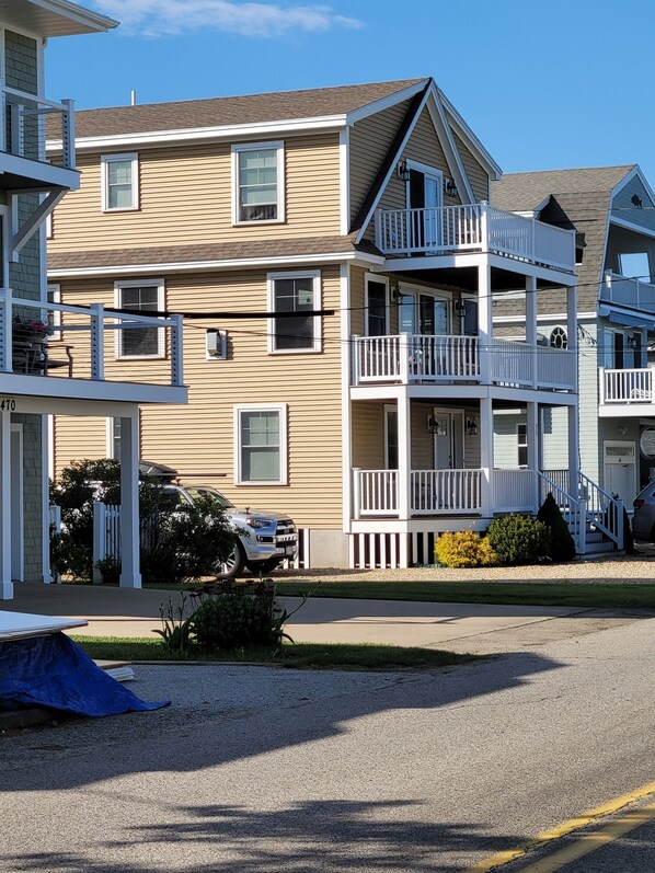 A multi-story building with a balcony on the second floor, a garage, and a driveway. - Great home minutes from beautiful Moody Beach, for the perfect beach vacation! (Wells)