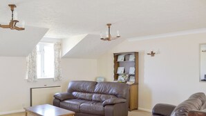 A living room with a brown leather sofa, a wooden coffee table, and a bookshelf. - Smugglers Haunt - UK44513 (Hope Cove, near Kingsbridge)