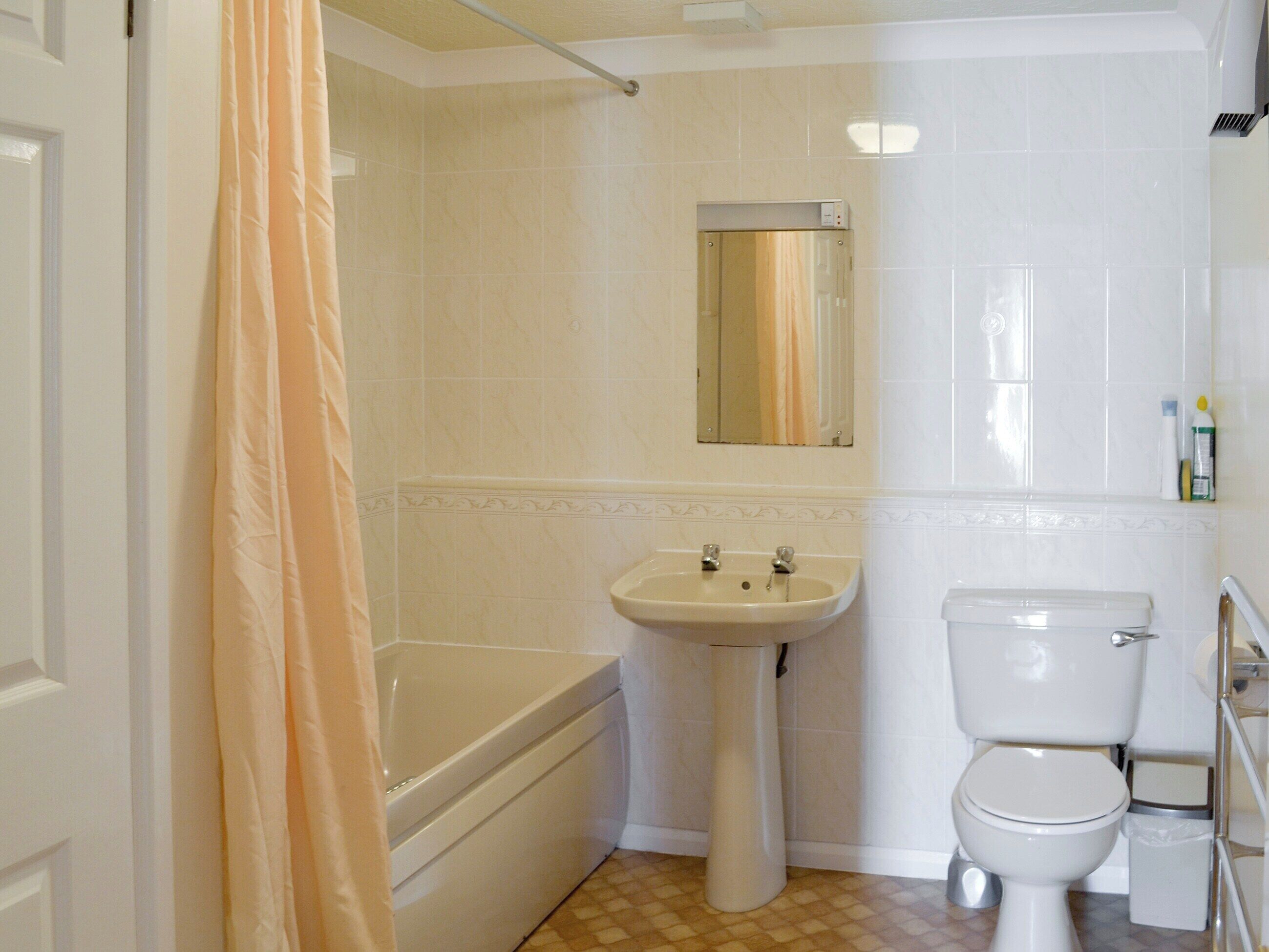 A bathroom with a bathtub, sink, toilet, and a shower curtain.