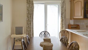 Une salle à manger avec une table en bois, six chaises et un ensemble de sous-verres.