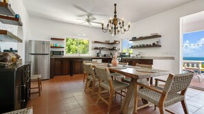 Una cocina amplia con comedor, una araña y vista al mar.