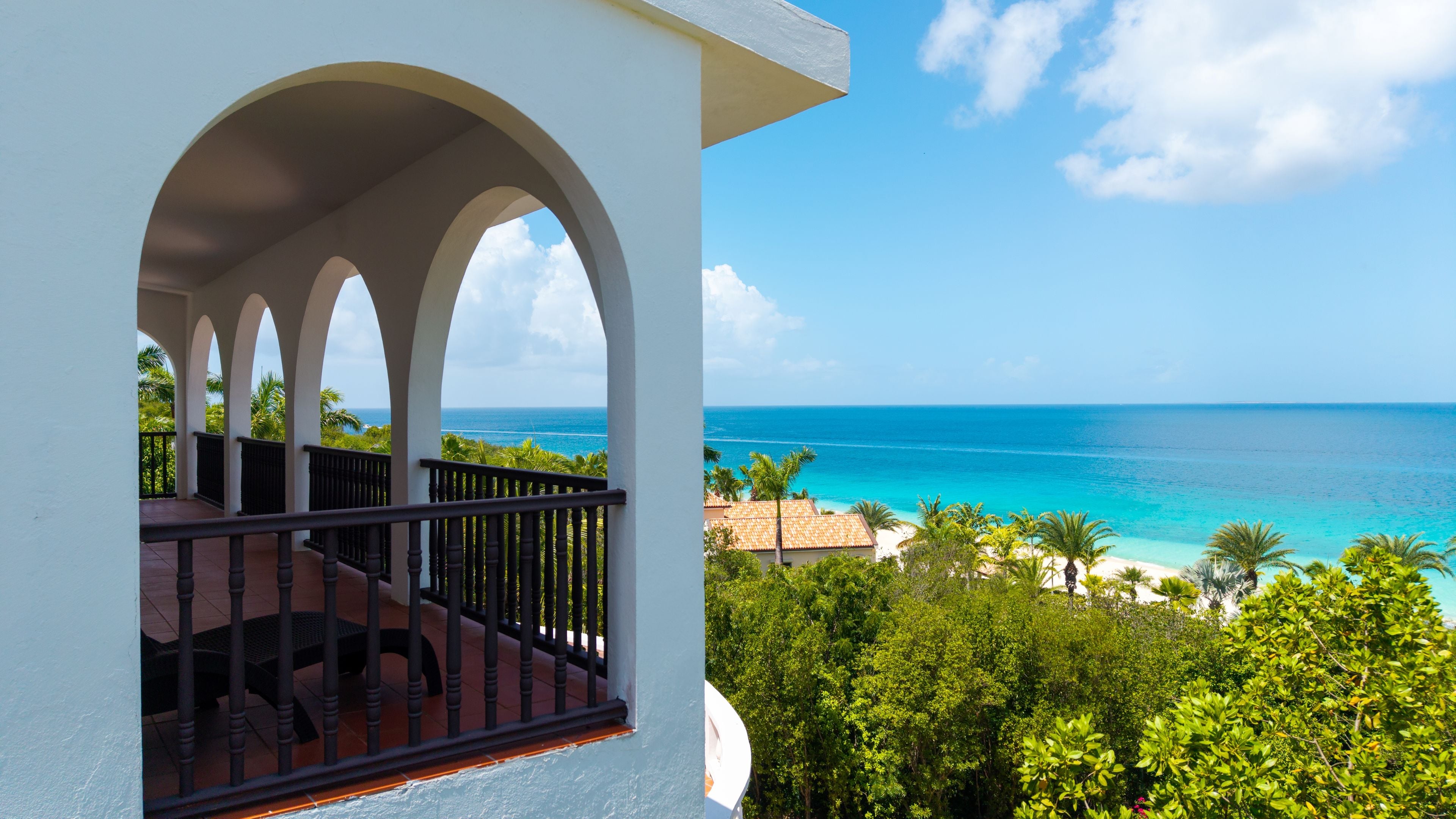 A balcony with a view of the ocean and a tropical landscape.